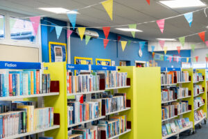 Colourful books sit on bookshelves while bunting hangs across the ceiling at Polesworth library